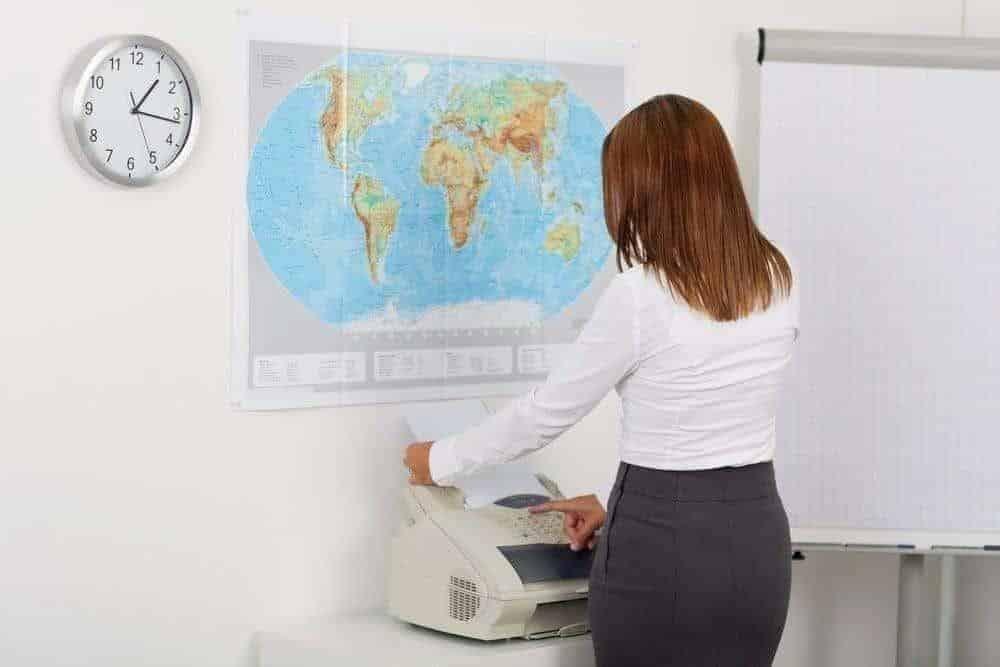 Portrait of happy businesswoman using fax machine in office